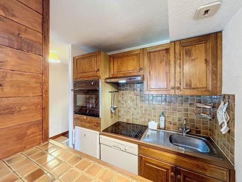 une cuisine avec des armoires en bois et un évier dans l'établissement Chalet à Chamonix, 54m², 3 chambres, 6 personnes - 16 Clos des Outannes, 74400 Chamonix-Mont-Blanc - FR-1-507-79, à Chamonix-Mont-Blanc