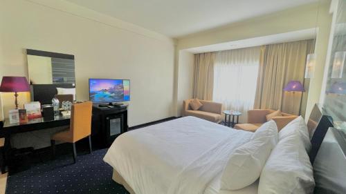 a hotel room with a bed and a desk at Swiss-Belhotel Silae Palu in Palu