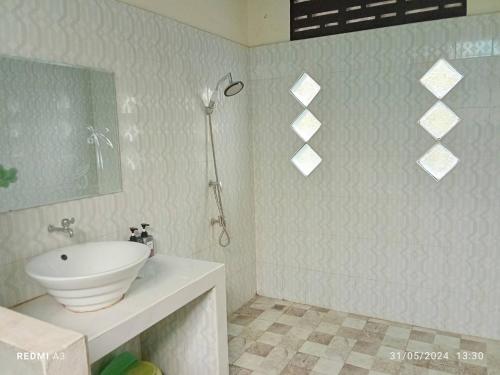 a white bathroom with a sink and a mirror at Maidok Homestay(ไม้ดอกโฮมสเตย์) in Ban Pak Ba Ra