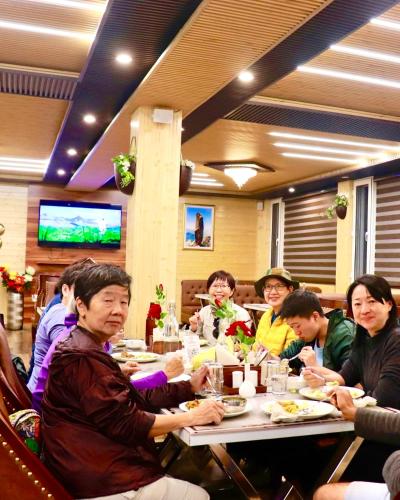 a group of people sitting at a table eating food at Hotel Rollingrang in Kalpa