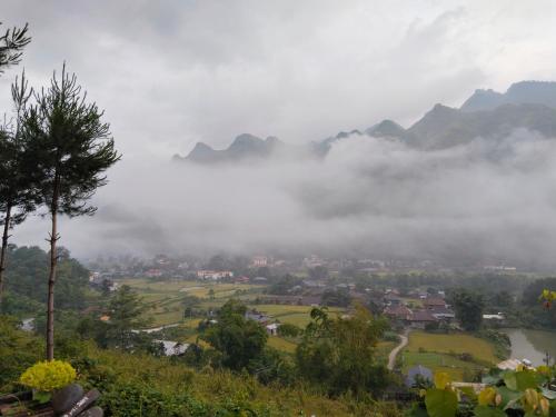 a town in a valley with fog and mountains at Tày Cốc Pảng Homestay in Làng Cac