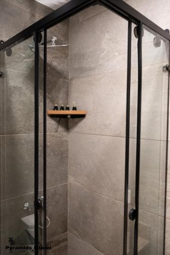a shower with a glass door and a shelf at Pyramids Island in Cairo