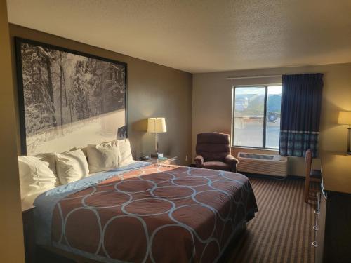 a hotel room with a bed and a chair and a window at Super 8 by Wyndham Portage in Portage