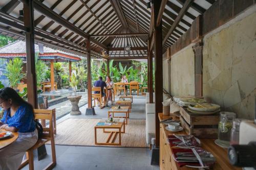 a woman sitting at a table in a restaurant at Ubud Aura Retreat in Ubud