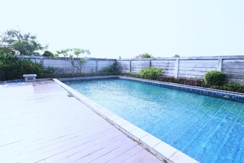 a large swimming pool with a wooden deck at The Enviro Nusantara By Reccoma in Cibeber