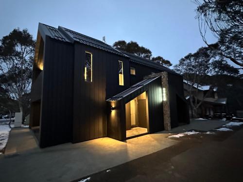 a black house with lights on the side of it at RAM, alpine getaways in Dinner Plain