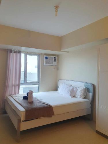 a bedroom with a white bed with a window at Avida Riala Tower one 1402 IT Park in Cebu City