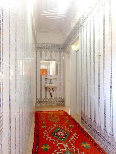 a room with a red rug on a wall at Maison d'hôtes afoulki tafraout in Tafraoute