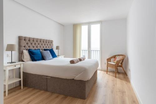 a white bedroom with a large bed with blue pillows at New apartment in the heart of the center in Santander