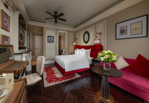 a bedroom with a white bed and a red couch at Hôtel de l'Amour Tam Đảo in Tam Ðảo