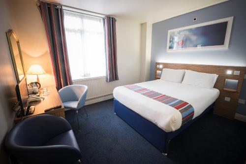 ダブリンにあるトラベロッジ ダブリン シティ ラスマインズのベッド、デスク、椅子が備わるホテルルームです。