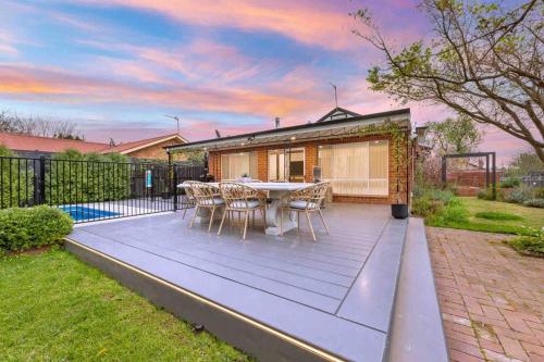 a deck with a table and chairs in a backyard at Ambience on Crampton in Wagga Wagga