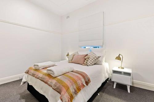 a white bedroom with a bed with pillows on it at Ambience on Crampton in Wagga Wagga
