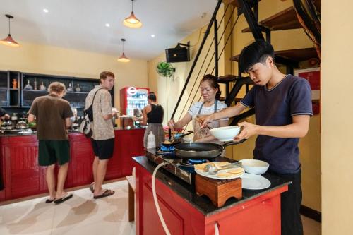 a group of people standing in a kitchen preparing food at Harmony Old Town Hostel and Pool Bar in Hoi An