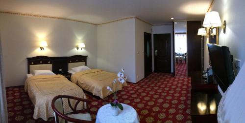 una camera d'albergo con due letti e una televisione di Hotel Colosseum a Olecko