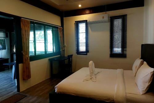 a bedroom with a bed with white sheets and windows at Suanmali Samui in Lamai