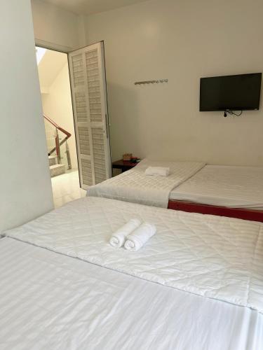 a bedroom with two beds with white sheets and a flat screen tv at Nguyên Thanh Hotel in Ho Chi Minh City