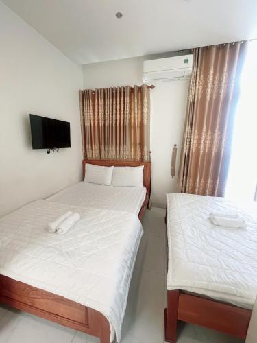 a bedroom with two beds and a television in it at Nguyên Thanh Hotel in Ho Chi Minh City