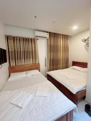 two beds in a small room with curtains at Nguyên Thanh Hotel in Ho Chi Minh City