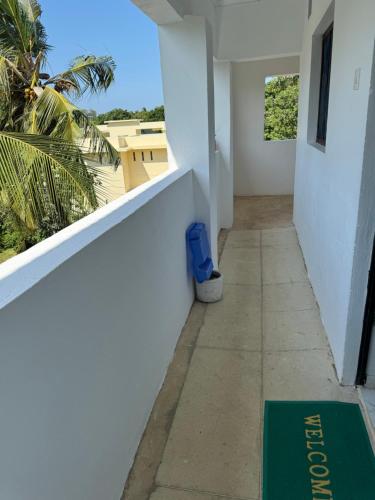 a hallway of a white building with a green welcome mat at Wind&Waves Beach Apartment in Diani Beach