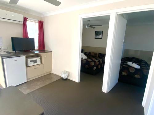 a room with a living room with a tv and a couch at High Street Motor Inn in Stanthorpe