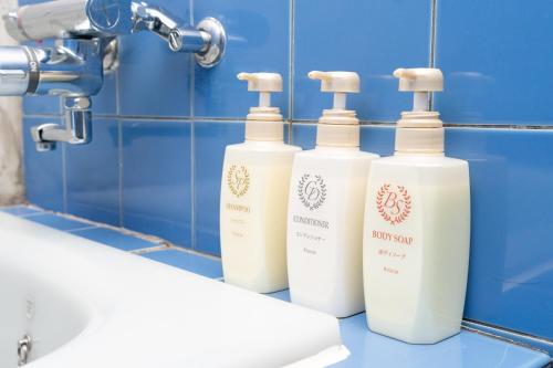 three bottles of soap sitting on a counter in a bathroom at Tokyo Guest House Ouji Music Lounge in Tokyo