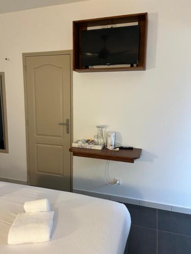 a bedroom with a bed and a television on the wall at Hôtel Les Embruns Du Baril in Basse Vallée