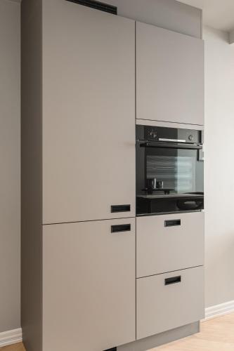 a kitchen with white cabinets and a microwave at Bryggen // Fløyen Living in Bergen