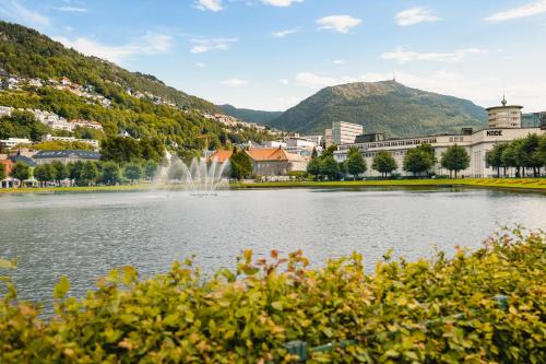 a lake with a fountain in front of a city at Bryggen // Fløyen Living in Bergen