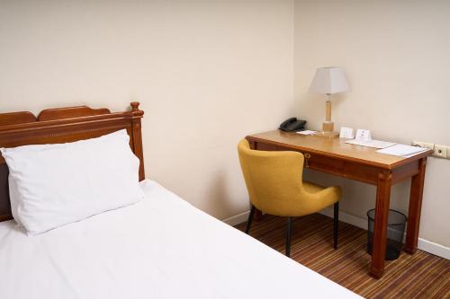 a hotel room with a desk and a bed and a phone at Almaty Hotel in Almaty