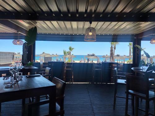 un restaurant avec des tables et des chaises et une vue sur l'océan dans l'établissement Marina 2 , appartement vue mer exceptionnelle, à Saint-Cyprien