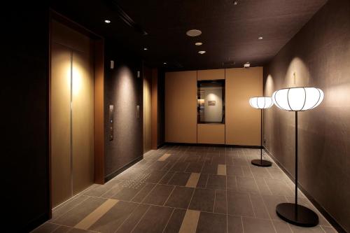 a hallway with two lights on the walls and a tile floor at Hotel Intergate Kyoto Shijo Shinmachi in Kyoto