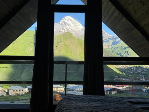 a view of a mountain from a bedroom window at Checkin Kazbegi in Stepantsminda