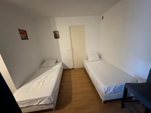 deux lits dans une chambre aux murs blancs dans l'établissement Appartement en rez-de-jardin de Villa, à Cogolin