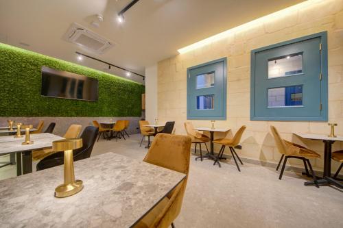 a restaurant with tables and chairs and a tv on the wall at 23 Boutique Hotel in Il-Furjana