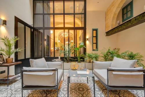 a living room with white furniture and plants at 23 Boutique Hotel in Il-Furjana