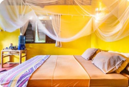 1 dormitorio con 1 cama grande y pared amarilla en Kuta Mountain Bungalows, en Kuta Lombok