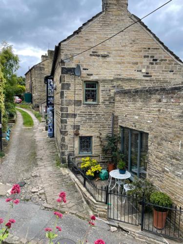 an old brick building with flowers on a fence at The Therapy Rooms Holmfirth Holiday Let in Holmfirth