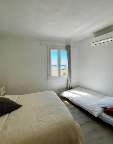 une chambre avec deux lits et une fenêtre dans l'établissement Magnifique appartement devant la plage, à Propriano