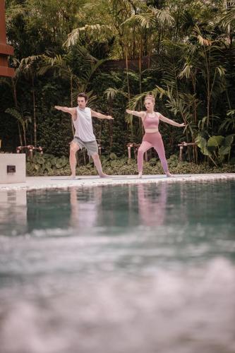 a man and a woman standing next to a swimming pool at Nysa Hotel Bangkok Sukhumvit 11 in Bangkok