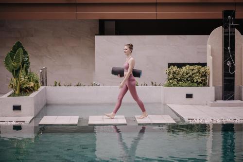 a woman walking on a platform next to a swimming pool at Nysa Hotel Bangkok Sukhumvit 11 in Bangkok