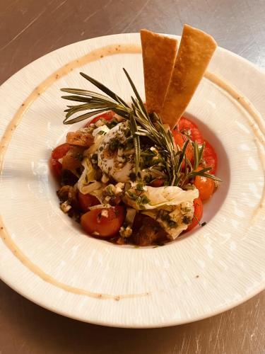 a white plate with a dish of food on a table at Hostellerie Au rendez-vous des amis in Chaumont