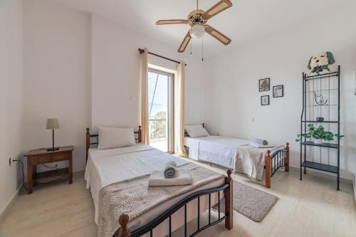 a bedroom with two beds and a ceiling fan at Seaside escape apartment in Saronida