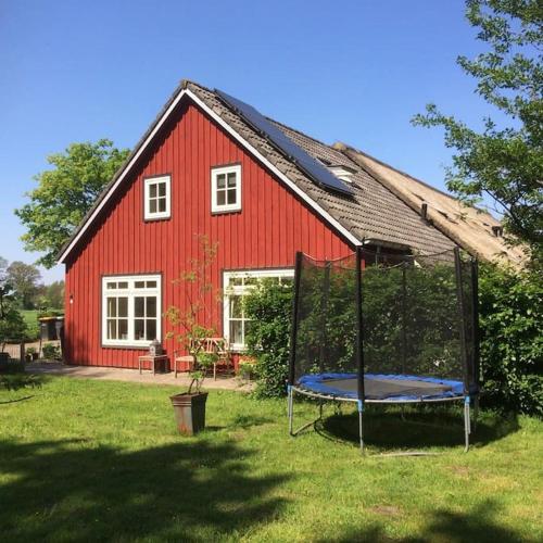 a red barn with a trampoline in front of it at Gastenverblijf Op zijn Zweeds in Echten