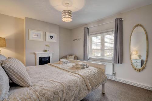 une chambre avec un lit, un miroir et une fenêtre dans l'établissement April Cottage by Winterton Cottages, à Winterton-on-Sea