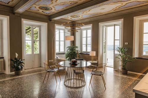 a dining room with a table and chairs and windows at Villa Antica Colonia SPA & Wellness in Pettenasco