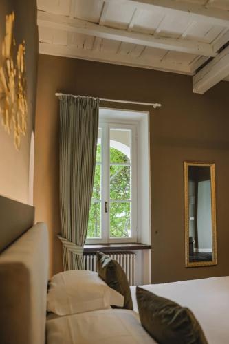 a bedroom with a window and a couch and a mirror at Villa Antica Colonia SPA & Wellness in Pettenasco