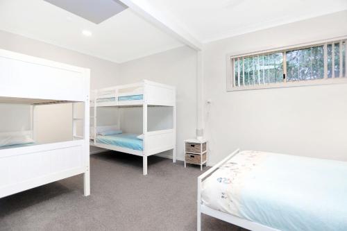 a white bedroom with two bunk beds and a window at Seaside Sanctuary in Hawks Nest
