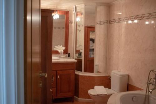 Un baño con inodoro, lavabo y espejo. en Domus Meus, en Mastambás
