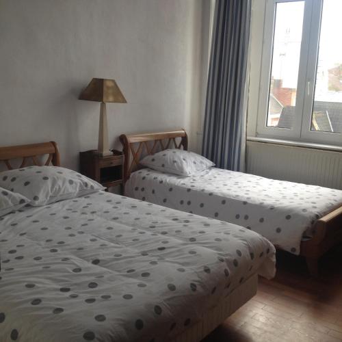 two twin beds in a room with a window at Chambres d'hotes Villa Faidherbe B&B in Dunkerque